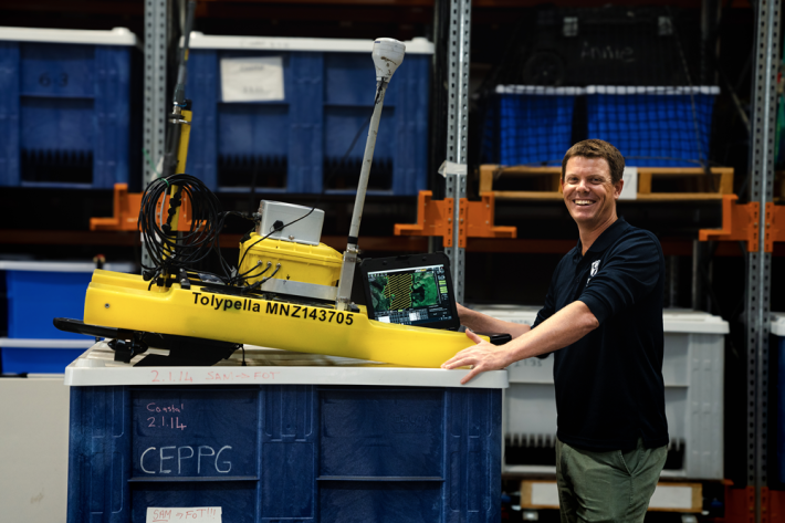 Freshwater ecologist Dr Daniel Clements tinkers with an autonomous vehicle kitted out to detect the invasive lagarosiphon using AI.