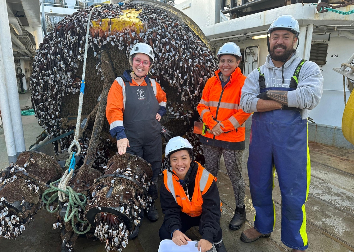 Yvonne, Antony, and Laura with Benita Murray of NEMA inspect the marine growth on a DART mooring