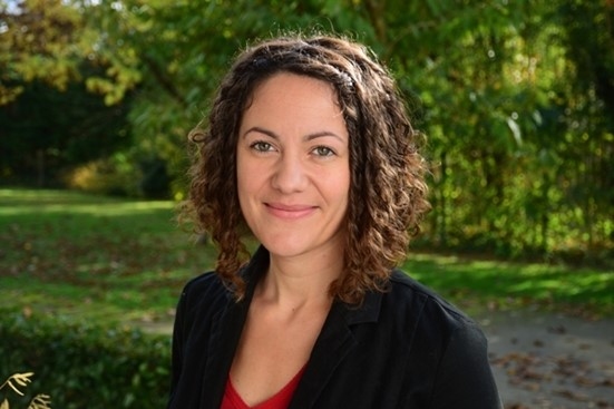 Headshot of Karine Borne, Water Quality Scientist, smiling in business casual, taken outside with green lawn and trees in the background
