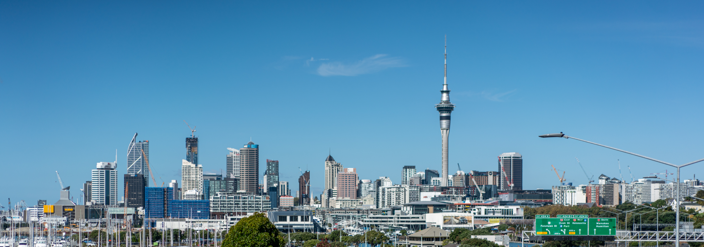 Auckland cityscape with view of Sky tower, motorway and the harbour, against clear blue skies