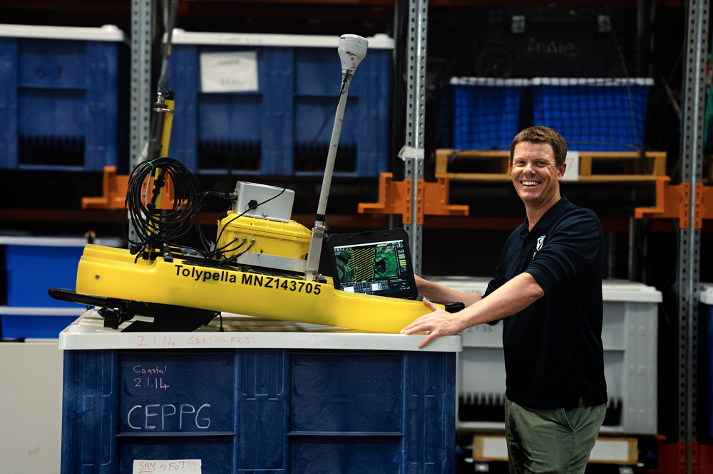 Freshwater ecologist Dr Daniel Clements tinkers with an autonomous vehicle kitted out to detect the invasive lagarosiphon using AI.