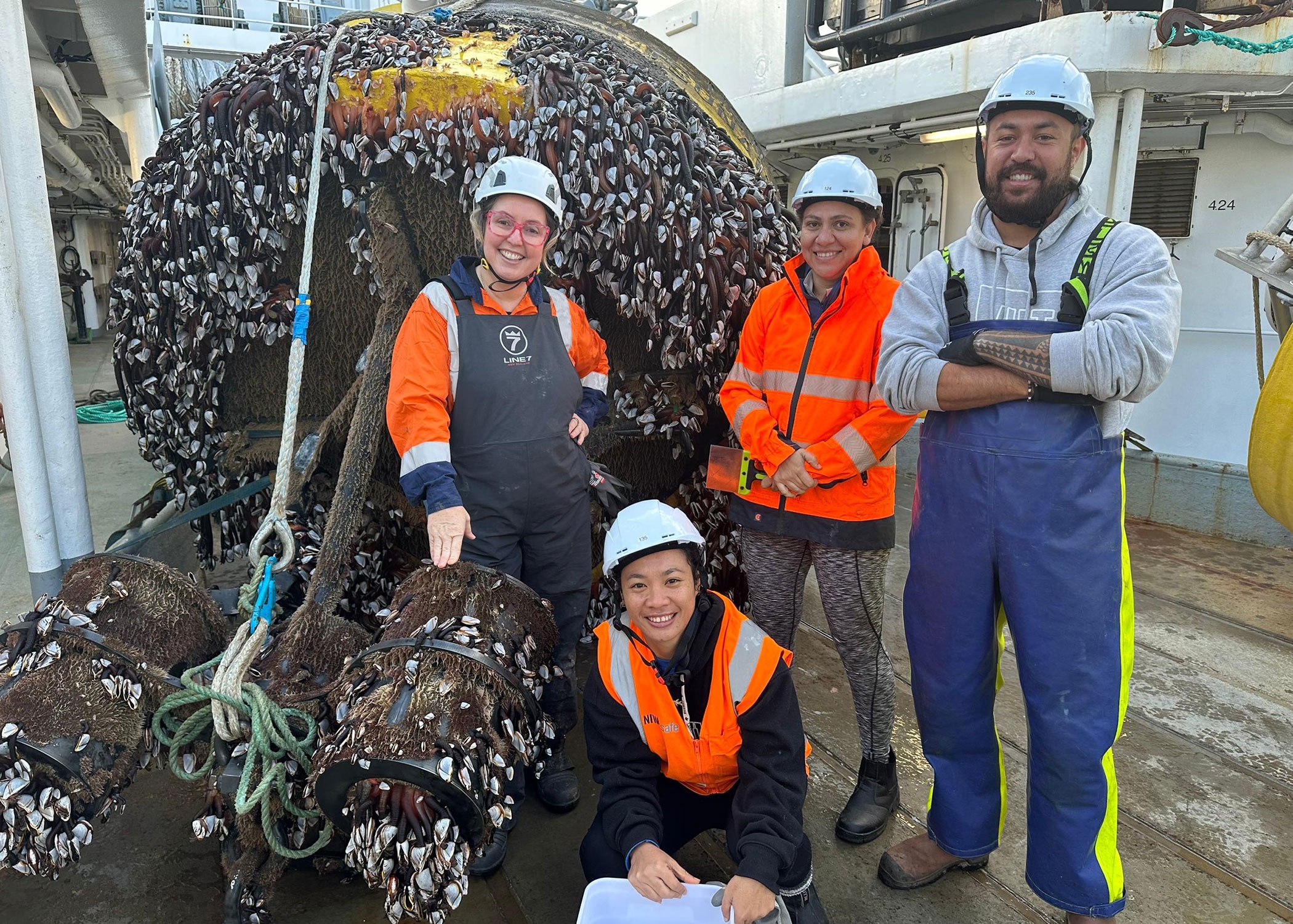 Yvonne, Antony, and Laura with Benita Murray of NEMA inspect the marine growth on a DART mooring